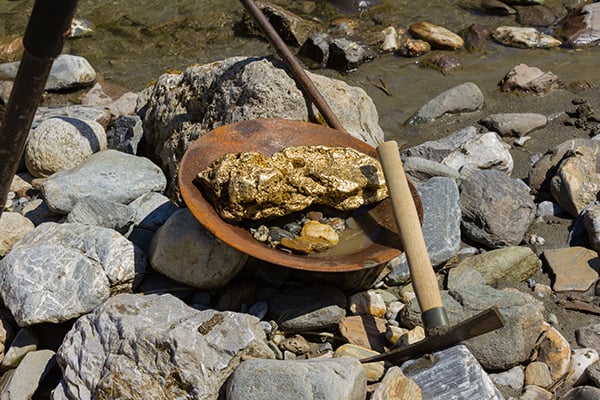 Gold nuggets in a pan with pick axe